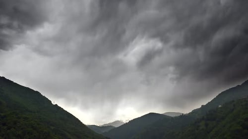 Dicke dunkle Stratonimbuswolken bedeckten das Tal zwischen bewaldeten Bergen
