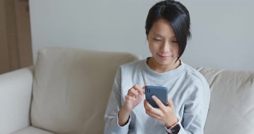 Woman Using Smartphone on Couch at Home