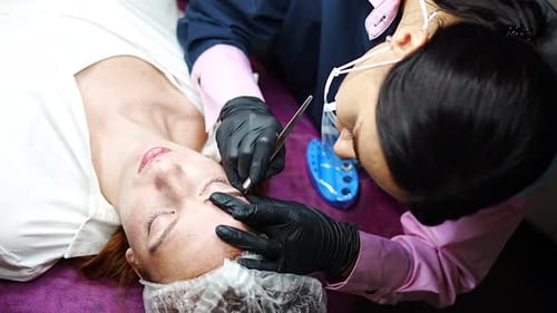 Woman receiving eyebrow treatment at beauty salon