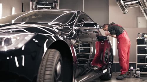 Young Man Polishing a Car in a Shop