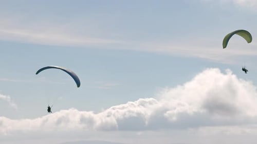 Die Leute versuchen Paragliding mit Fallschirmen gegen Wolken zu fliegen