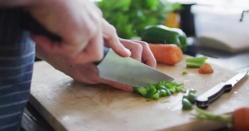 Closeup of mans hand cutting green pepper on the cutting board