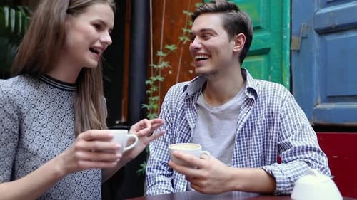 Couple In Cafe. Young People Drinking Coffee And Communicating