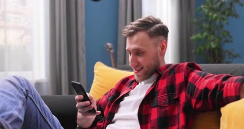Man Relaxing on Couch Using Smartphone