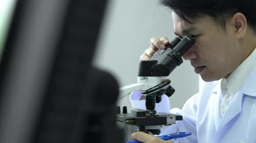 Scientist male looking microscope in laboratory