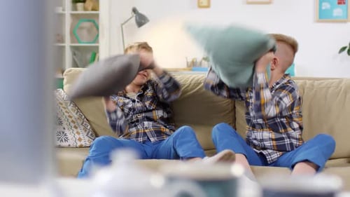 Carefree Twin Boys Having Pillow Fight on Couch