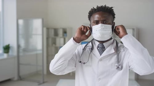 Friendly Doctor Removes Surgical Mask in Clinic