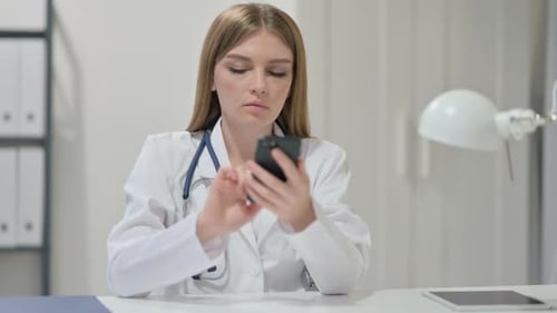Young Woman Doctor Uses Mobile Phone in Office