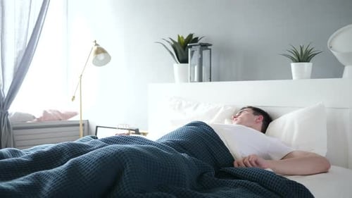 Man Waking Up and Stretching in Bed