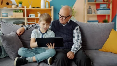 Boy and Grandfather Using Tablet Together on Couch