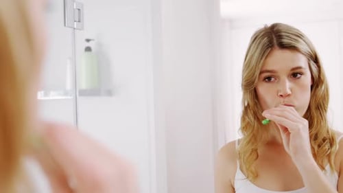 Woman Brushing Teeth in Bright Bathroom