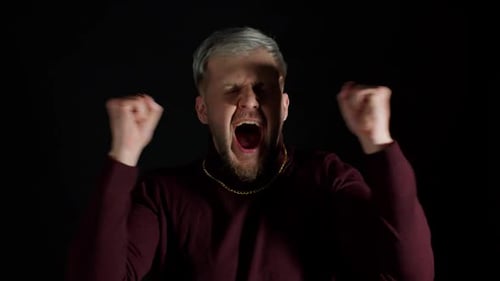 Man Pumping Fists in Celebration on Black Background