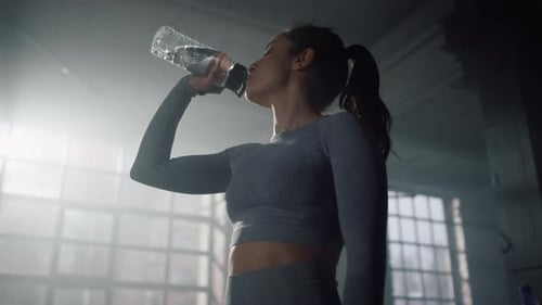 Sportswoman Drinking Water in Gym