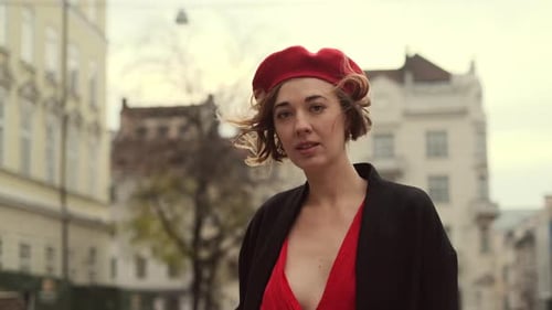 Portrait Of Stylish Young Woman In Red Beret. Woman Looking At Houses On City Square.