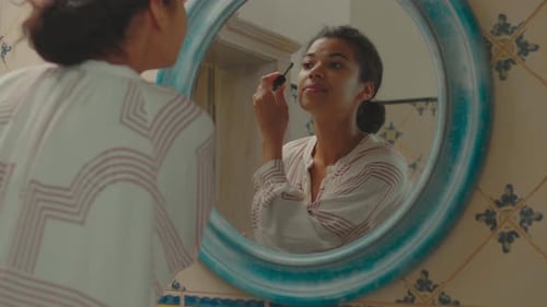 Close Up of 20s African American Woman Applying Mascara Looking at Mirror in Bathroom