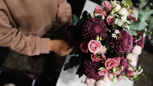 Le travail du fleuriste consiste à décorer un grand bouquet dans un magasin de fleurs en gros plan vu d'en haut