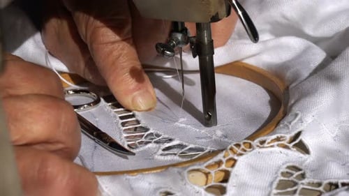 Uma velha costureira está trabalhando com uma máquina de costura
