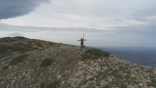 Male Hiker Standing on Peak and Victoriously Raising Arms Rejoicing Success
