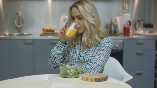 Woman Enjoys Healthy Salad and Juice in Kitchen