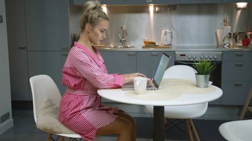 Young Woman Works on Laptop in Modern Kitchen