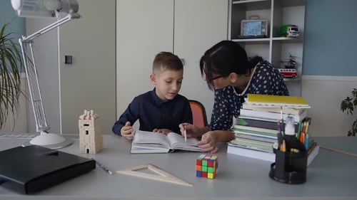 A Young Teacher Teaches a Primary School Pupil To Read Book Well Homework Explaining Homework