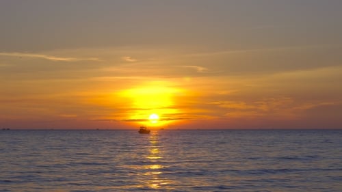 Shot of a Sunset on a Tripical Beach with a Silhouette of a Fishing Boat Close To the Sun
