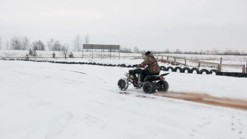 the Guy Is Riding an ATV on a Snow-covered Road in Winter