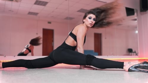 Hermosa bailarina hace las divisiones en la clase de baile, Atractiva bailarina de barra blanca en apretado