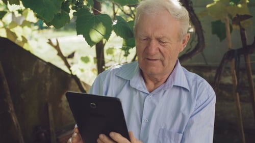 Happy Senior Emotionaly Using the Tablet in the Garden
