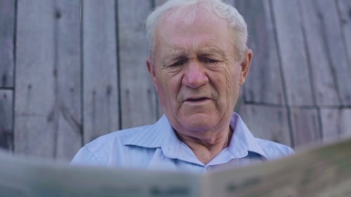 Senior Man Reads Newspaper Outdoors