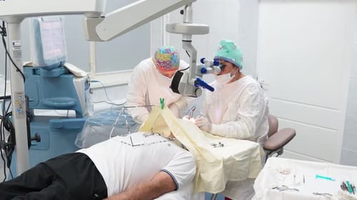 Two Female Surgeons Perform Eye Surgery with Microscope and Medical Instruments