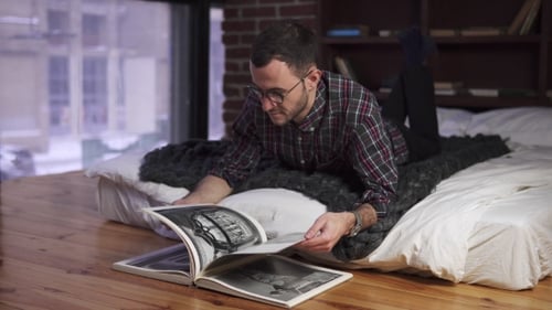 Man Lying on Bed and Leafing Through the Book