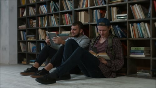 Estudiantes sentados frente a una estantería hablando