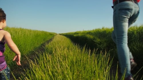 Girl Runs with Woman Holding Colorful Balloons in Field
