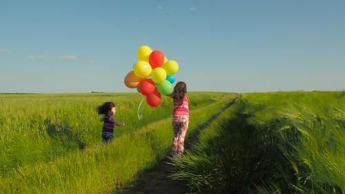 Girls Running with Colorful Balloons in Grassy Field