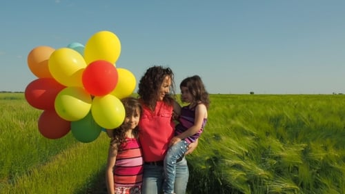 Mother and Daughters with Balloons in Green Field