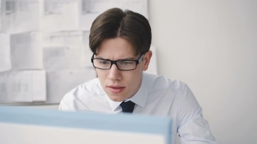Worried Businesman Working Diligently with Computer in Office