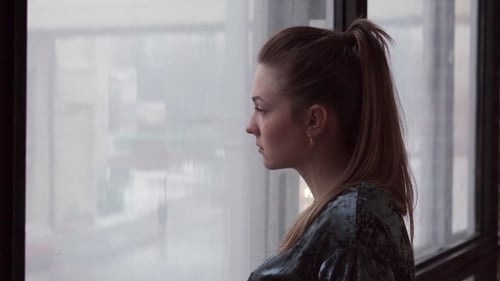 Woman Gazing Out Window in Apartment
