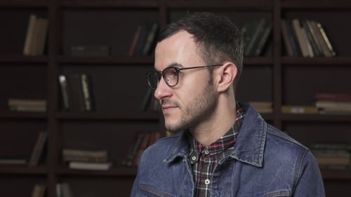 Man Smiling in Front of Bookshelf in Home