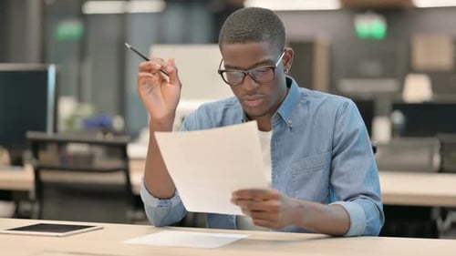 Young Man Reads Documents with Positive Reaction