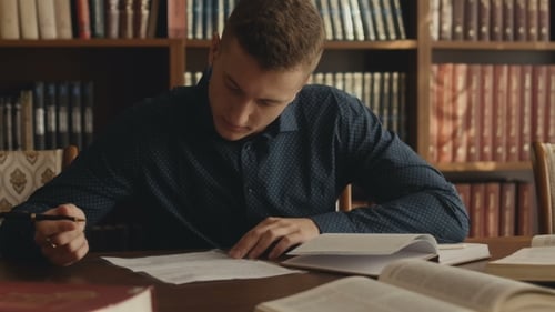 Young Adult Studying, Writing in Front of Bookshelf