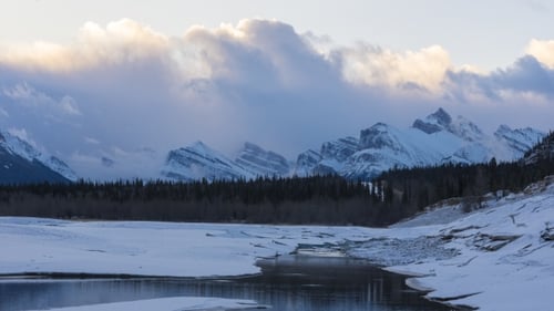 of Clouds Flowing Over Snowy Mountain Peaks at Sunrise
