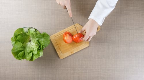 Küchenchef schneidet Tomaten auf Holzbrett