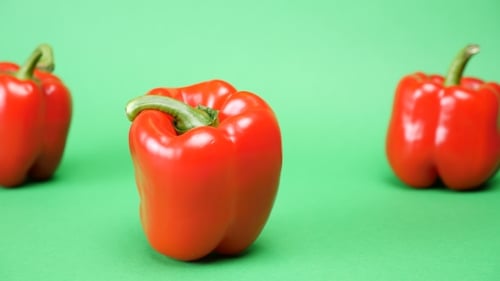 Five Sweet Red Peppers on Green Background