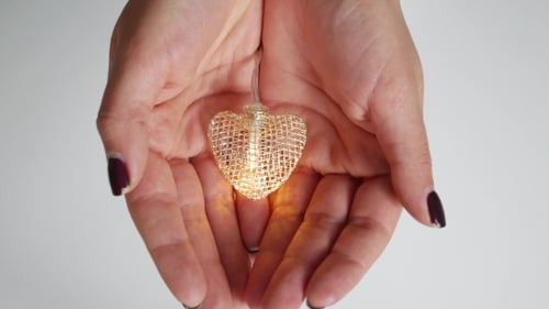 Hands Holding Heart Shaped Object on White Background