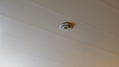 Die Hand einer Frau stößt zum Einschalten gegen eine energiesparende Glühbirne