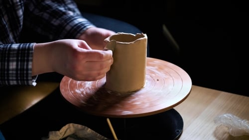 of Hands Working Clay on Potter's Wheel. Potter Shapes the Clay Product with Pottery Tools on the