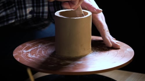 de mains travaillant de la pâte à modeler sur la roue du potier. Potter façonne le produit en argile à l'aide d'outils de poterie placés sur le