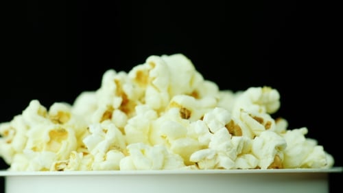 A Glass of Popcorn on a Black Background. Slowly Rotates