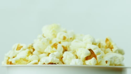A Glass of Popcorn on a White Background. Slowly Rotates